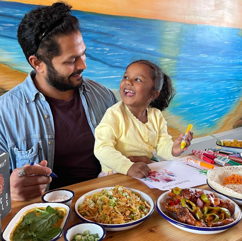 Man smiling at child with plate of food in front of them