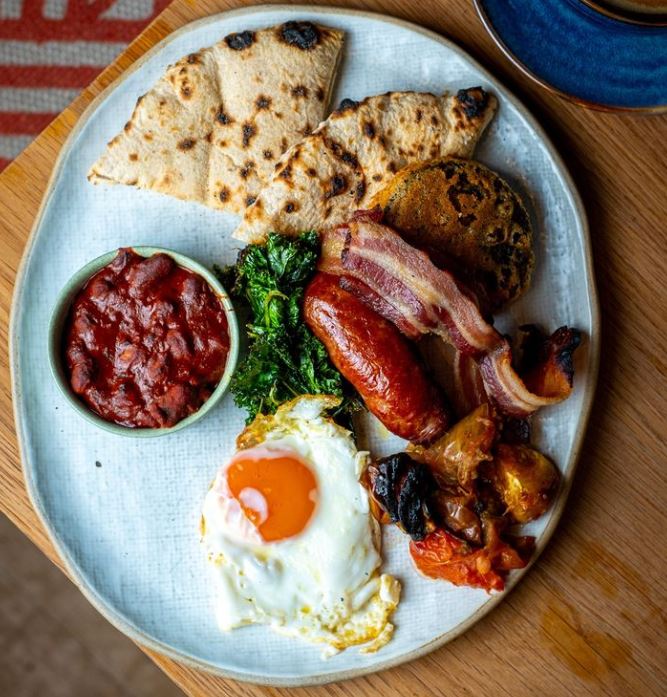 Cooked breakfast with egg, sausage, bacon, bread and beans