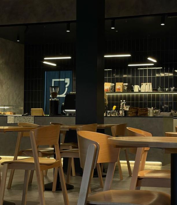 Inside coffee shop with dark walls and wooden chairs