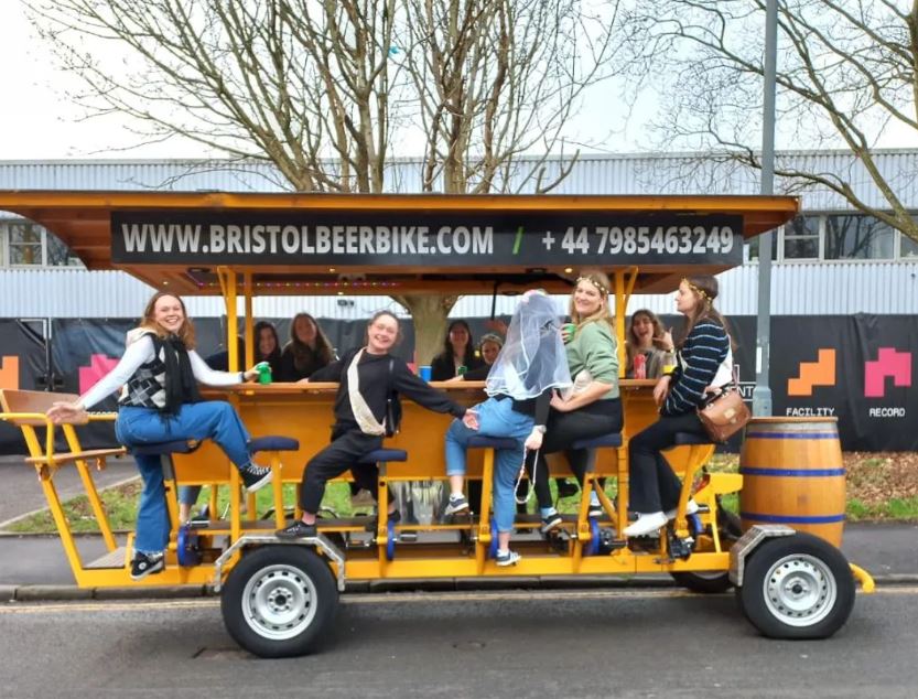 People posing on beer bike in hen do outfits