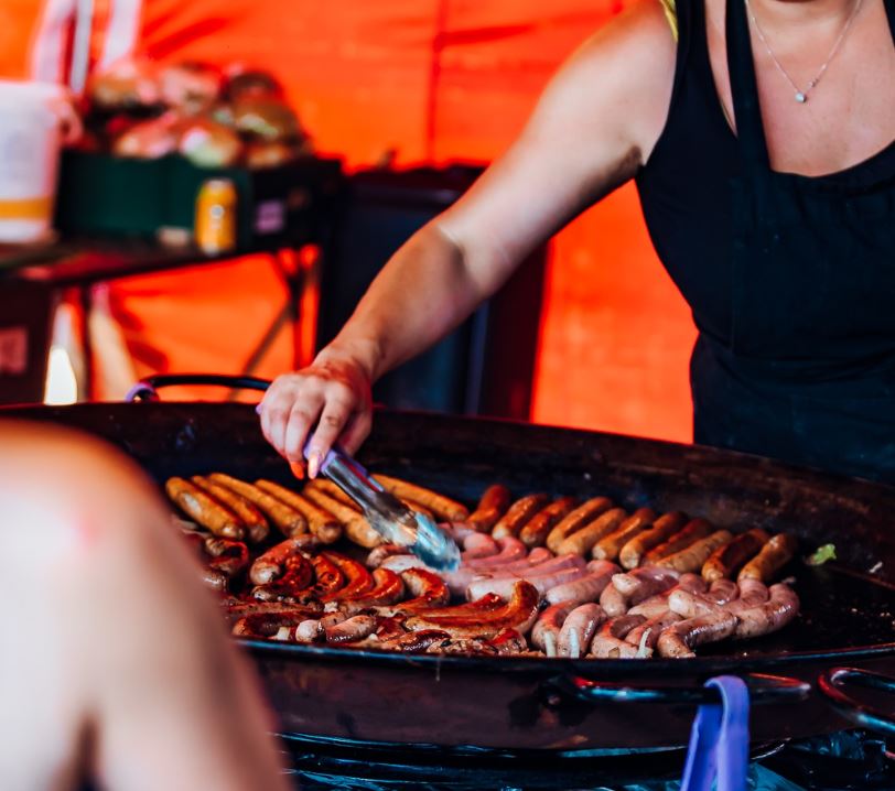 Person cooking a big skillet of sausages