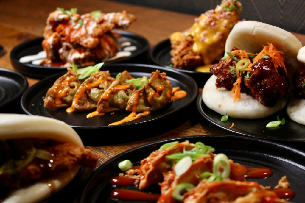 Selection of Asian-style dishes such as bao, dumplings and fried chicken with sauces