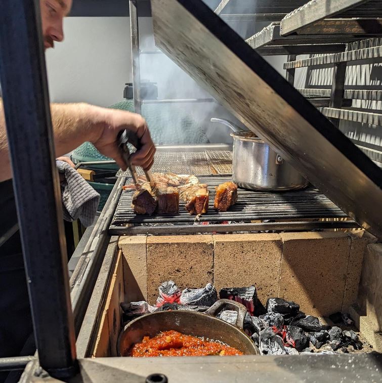 Person cooking meat on grill