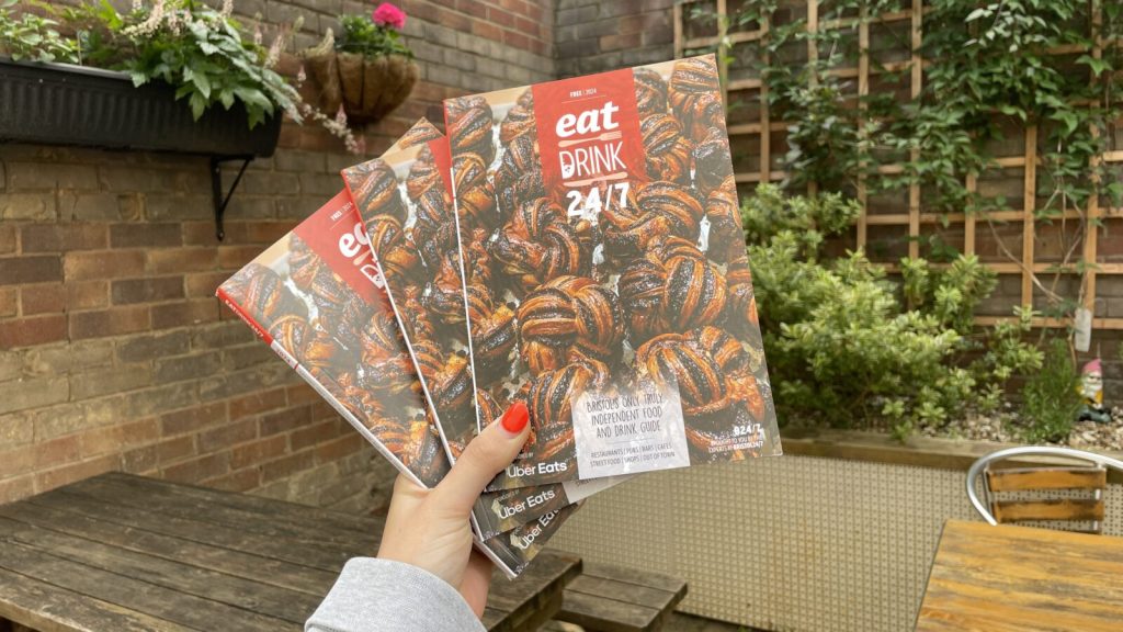 Copies of Eat Drink 24/7 guide being held up