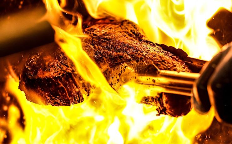 Pasture cooking steak over fire