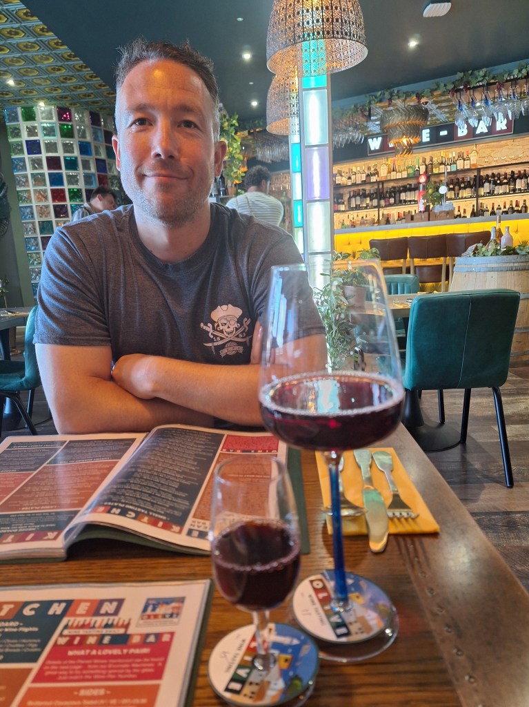Man sat at table with two glasses of red wine,one large and one small