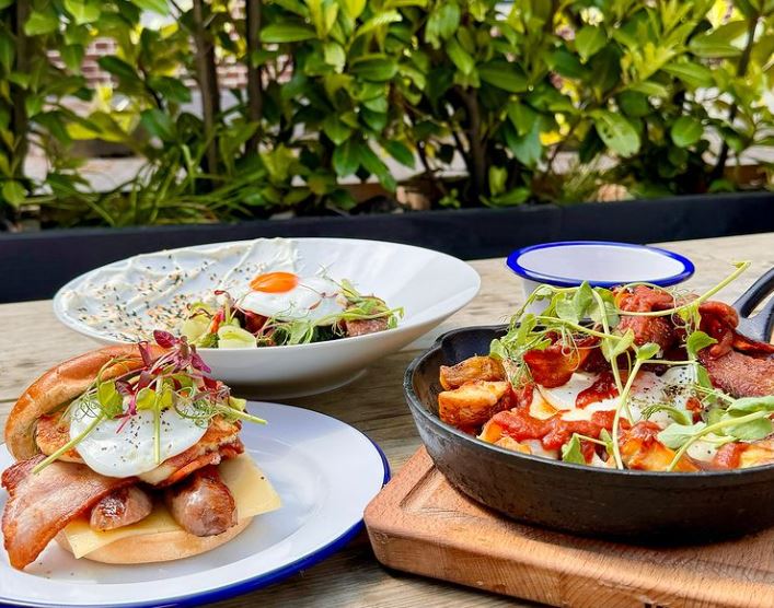 Selection of brunch dishes: sausage and egg bap, bacon hash in skillet