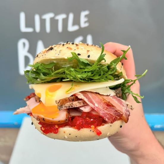 Hand holding filled bagel sandwich