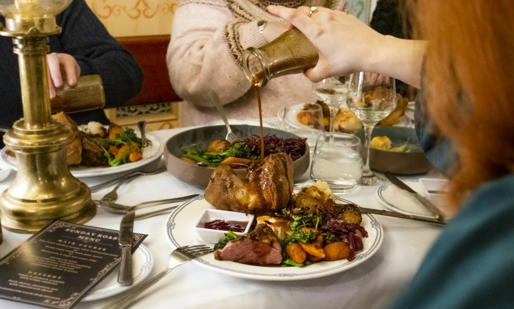Person pouring gravy on roast dinner